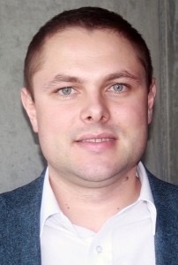 Professional headshot of a man in a white shirt and blazer