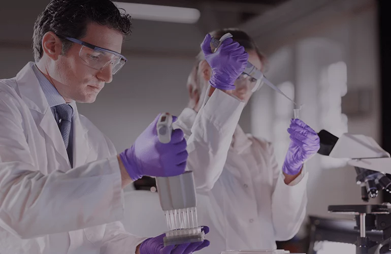 Two laboratory professionals handling pipettes and samples, illustrating precise analytical work
