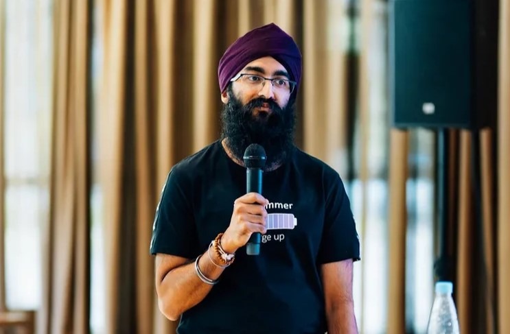 Man in turban speaking into microphone during software quality interview event