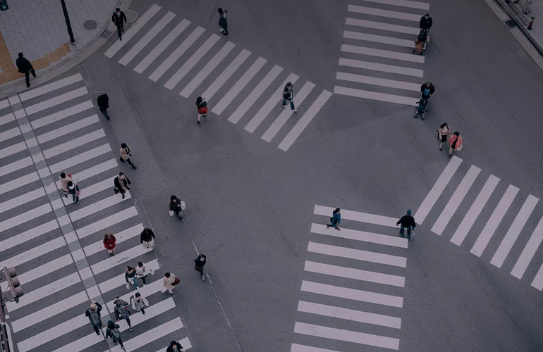 Aerial view of pedestrians crossing multiple crosswalks at a large city intersection