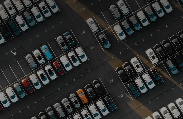 Aerial view of a large parking lot with neatly arranged rows of cars
