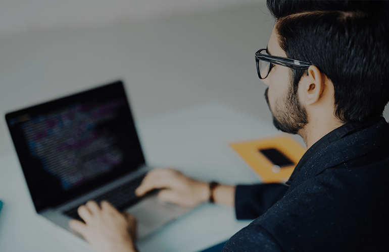 Developer working on a laptop, representing CMS solutions for ecommerce platforms