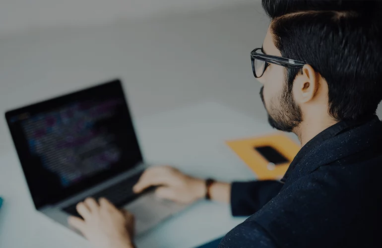 Developer working on a laptop, representing CMS solutions for ecommerce platforms