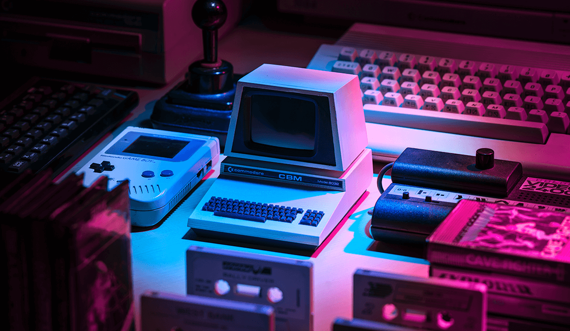 Retro gaming devices and a Commodore CBM Model 8032 on a desk under neon lighting