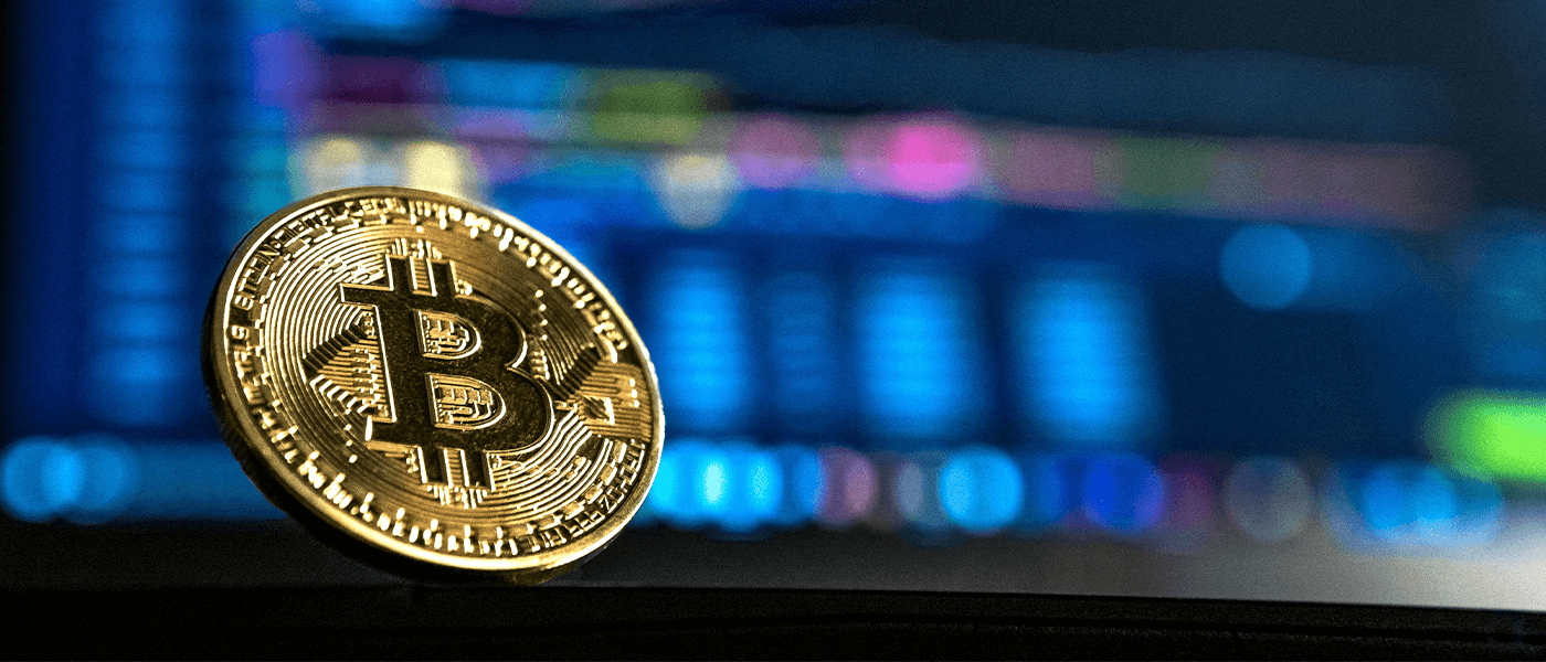 Bitcoin coin in front of blurred digital market charts representing blockchain technology testing