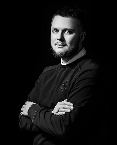 Black-and-white portrait of a bearded team member with arms crossed