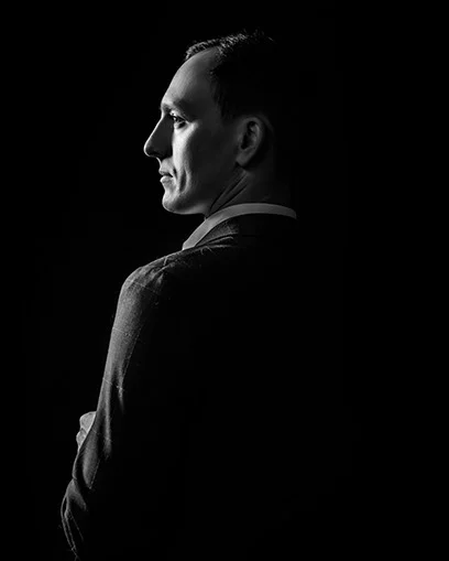 Black-and-white profile portrait of a business professional in a suit against dark background