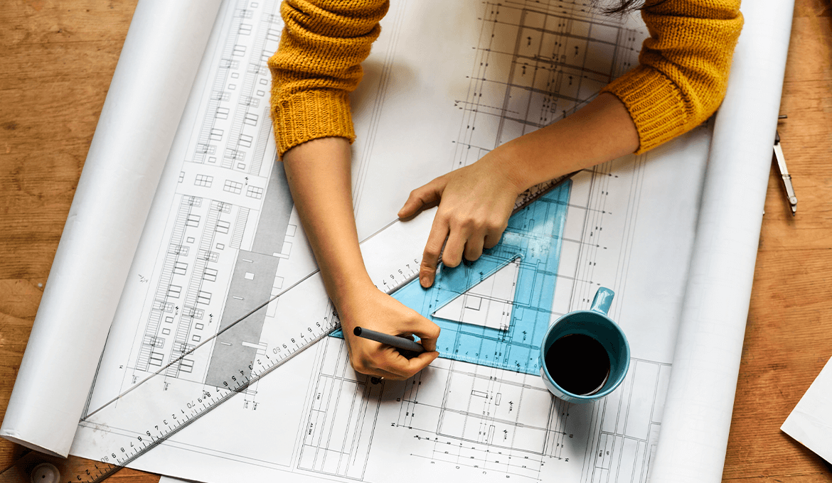 Engineer marking technical blueprint with rulers and coffee, representing precise performance testing planning