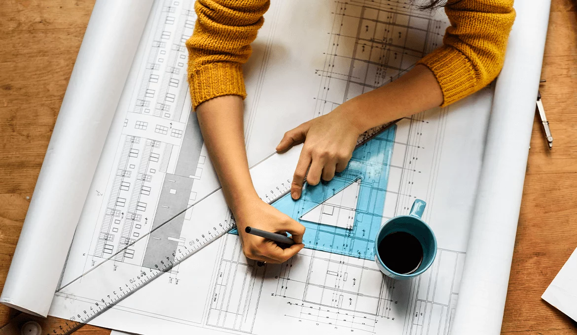 Engineer marking technical blueprint with rulers and coffee, representing precise performance testing planning