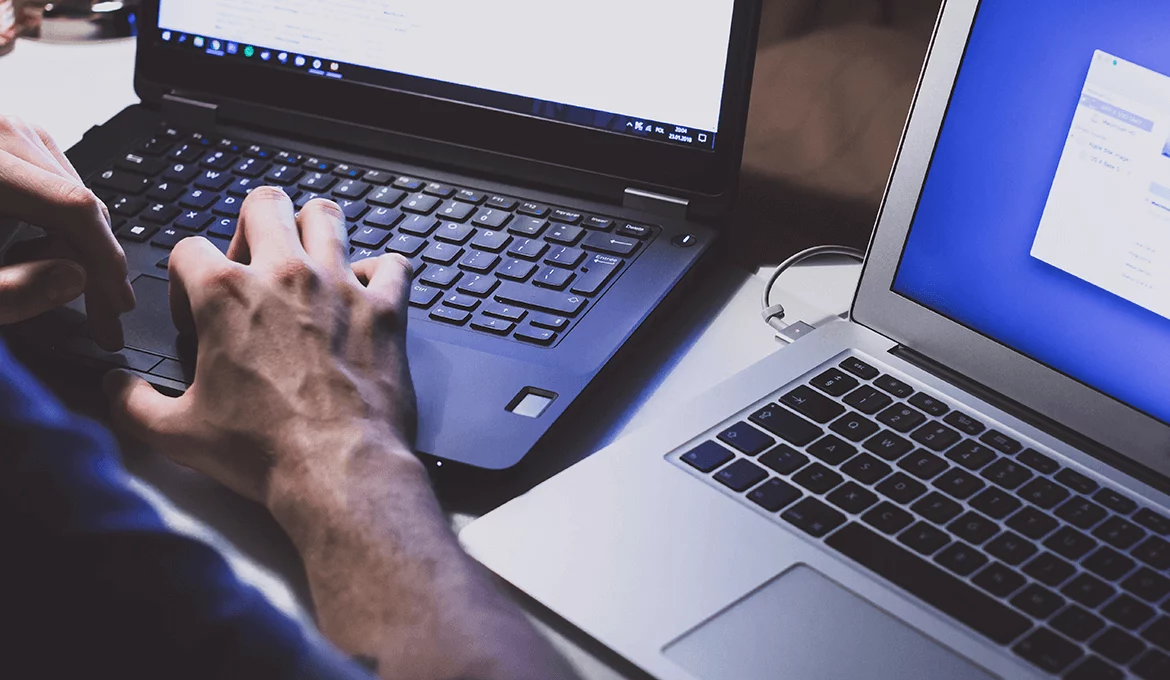 Engineer working on dual laptops in a software testing and system architecture setup