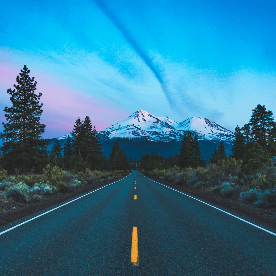 Straight highway leading toward snowcapped mountains, symbolizing performance, speed, and reliable progress