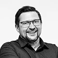 Smiling man wearing glasses in a professional black-and-white headshot