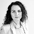 Professional headshot of a woman with curly hair in a light blazer