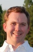 Portrait of Justin Rohrman smiling outdoors in a white shirt