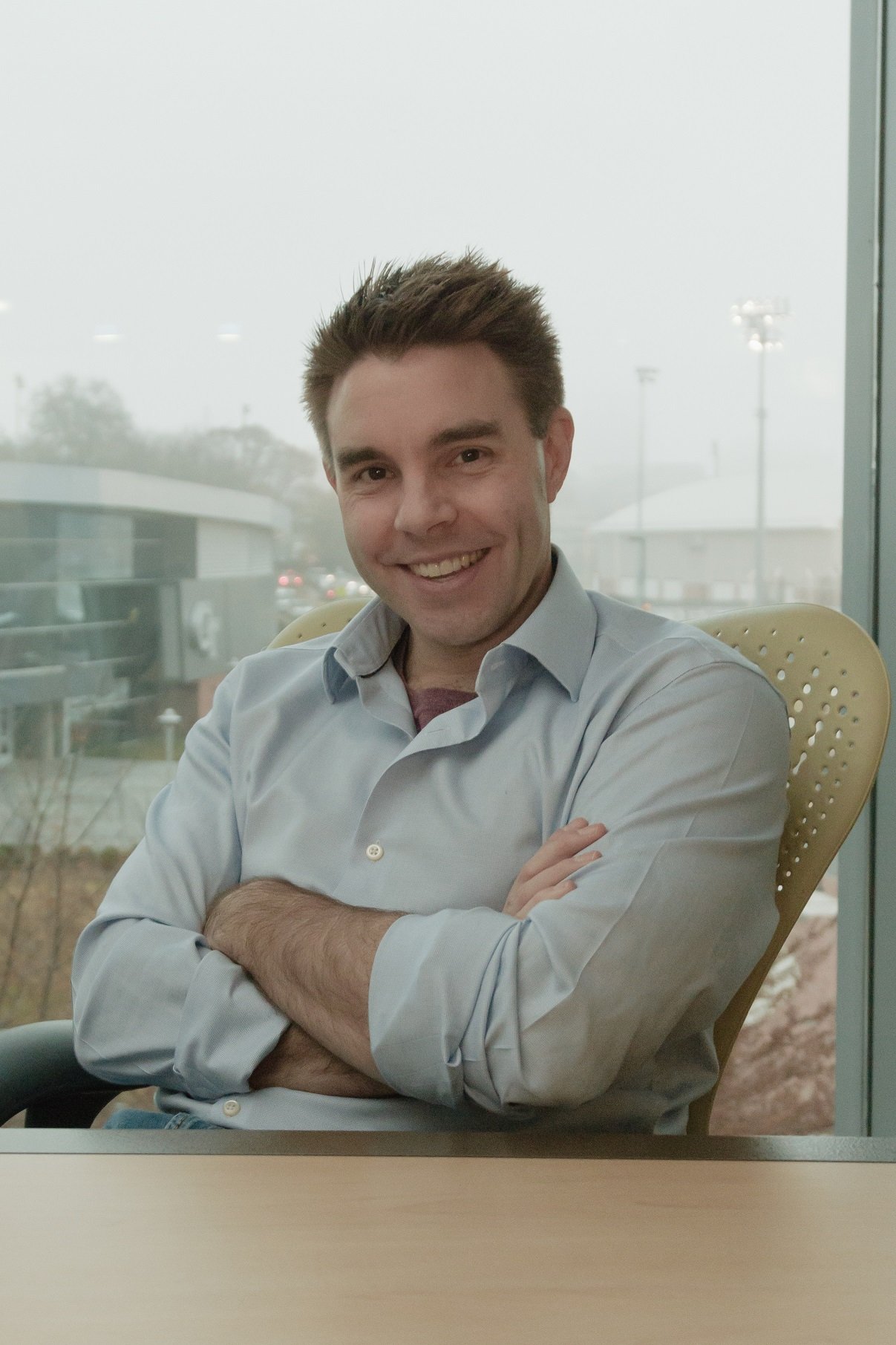 Smiling software professional seated with arms crossed in a modern office chair