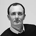 Black-and-white headshot of a man in business attire for author profile