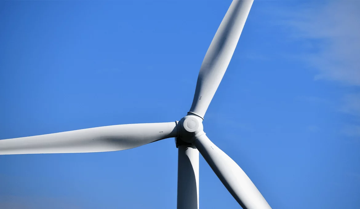 Close-up of a wind turbine against blue sky, symbolizing sustainability and innovation