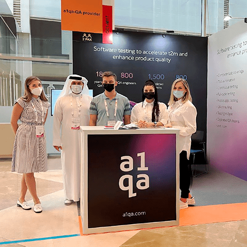 Five a1qa team members at exhibition booth with a1qa and a1qa-QA provider